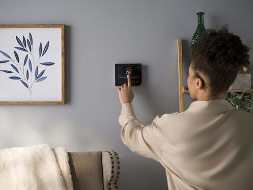 A young woman in Zebulon, NC checking the thermostat.