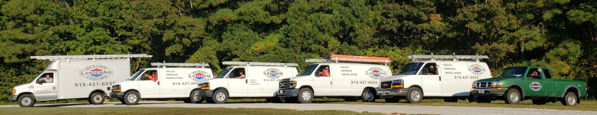 Landen work trucks lined up by a forest